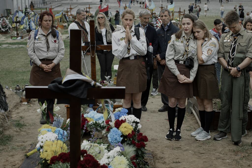 Mourners at the gravesite of a fallen soldier during his funeral in Lviv, Ukraine. In Lviv babies are born in a hospital just steps away from the military cemetery where Ukraine’s young soldiers are laid to rest. Photograph: Emile Ducke/The New York Times