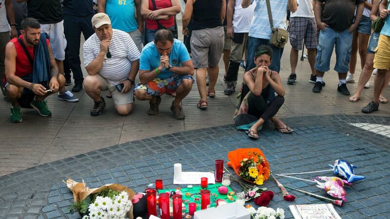 People mourn in front of candles and flowers placed on a Spanish artist Miro’s mosaic on the site of a van attack in Barcelona in which 13 people died. Photograph: EPA