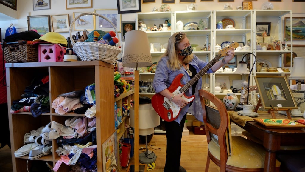Siobhán McGuinness of Making it Matter charity shop in Dún Laoghaire checks the price on an electric guitar for sale on the first day of reopening since Covid-19 restrictions were lifted. Photograph: Alan Betson