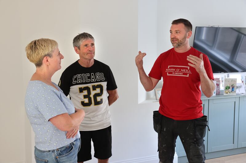 Pat Curran and his wife Breda in the newly rebuilt home with builder and plasterer Mark O’Neill. Photograph: Dara Mac Dónaill/The Irish Times