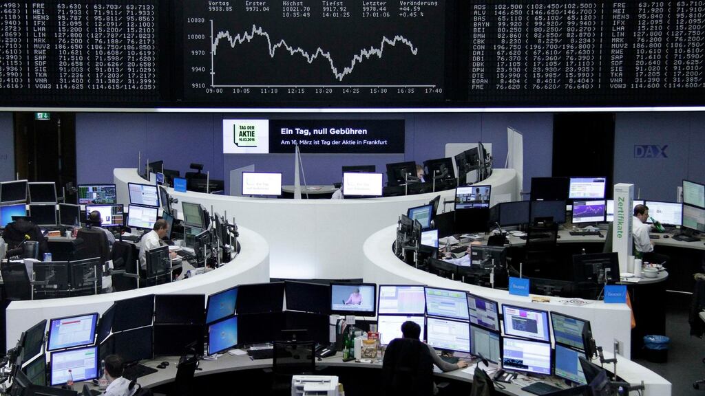 Traders work at their desks in front of the German share price index, at the stock exchange in Frankfurt, Germany.