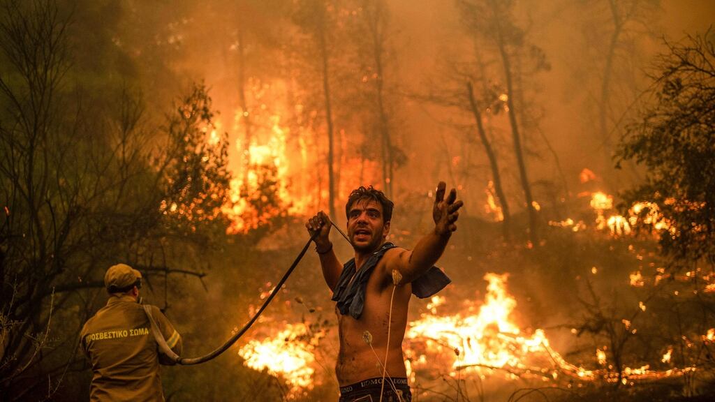 An Evia resident holds an empty water hose as fire rages on the Greek island: We must act now to avoid the most severe consequences of climate change. Photograph: Angelos Tzortzinis/AFP