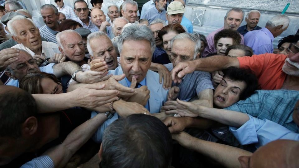 An employee of the National Bank of Greece (c) distributes priority tickets to pensioners queuing outside a bank branch in central Athens on Wednesday. Photograph: EPA