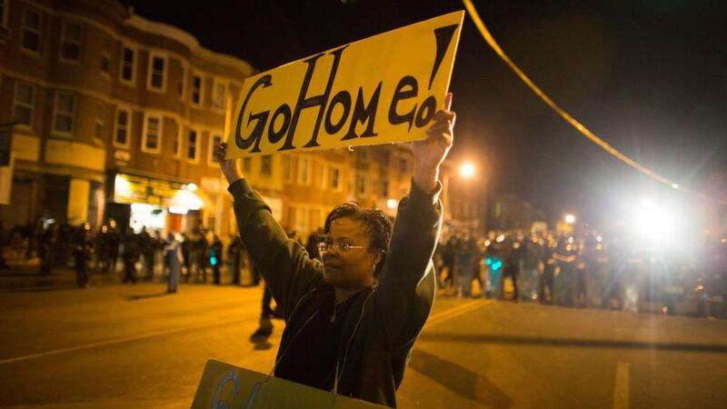 A woman holds a sign telling protesters to go home during a 10pm curfew in Baltimore, Maryland. The city remains under curfew following Monday’s riots. Photograph: John Taggart/EPA