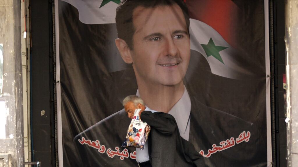 A Syrian man walks past a poster bearing a portrait of Syrian president Bashar al-Assad on a street in the capital Damascus. Opponents of Mr Assad expect the government to ignore the planned truce starting on Saturday. Photograph: Louai Beshara/AFP/Getty Images