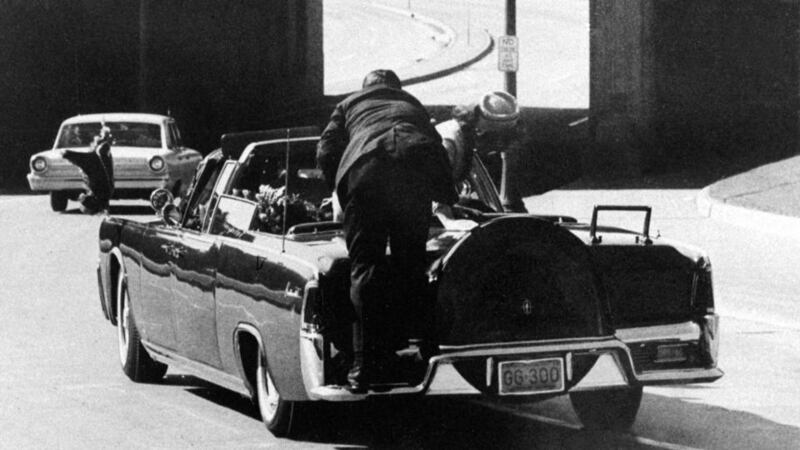 President Kennedy slumps down in the back seat of the presidential limousine after being fatally shot as it speeds along Elm Street toward the Stemmons Freeway overpass in Dallas. First lady Jackie Kennedy leans over the president as Secret Service agent Clint Hill pushes her back to her seat. Photograph: James Altgens/AP