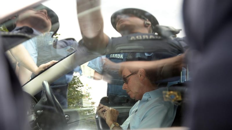 Alan Shatter using his phone as gardaí surround his car. Photograph: Dara Mac Dónaill / The Irish Times