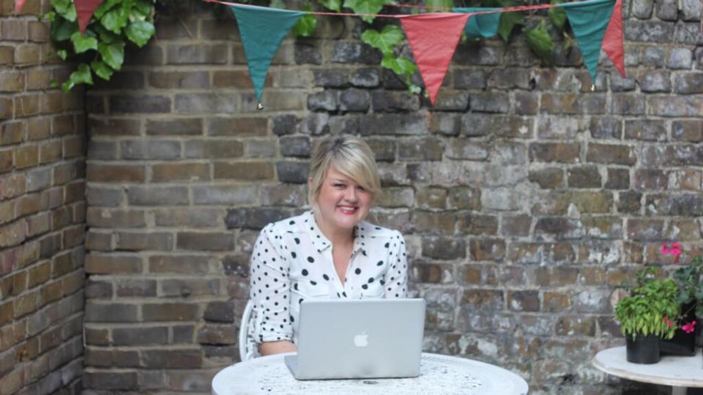 Catherine Conroy writing in her yard, with bunting and bells for company