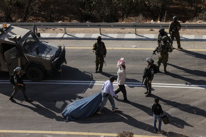Palestinian farmers carry bags of olives after their harvest was disrupted by Israeli settlers and halted by Israeli security forces in the West Bank village of Sa'ir, near Hebron. Photograph: Hazem Bader/AFP/Getty Images