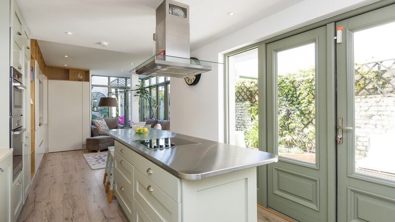 The kitchen, designed by Alan Moody Kitchens, is a lovely mix of stainless steel, oak, and hand-painted units in soft Farrow & Ball tones