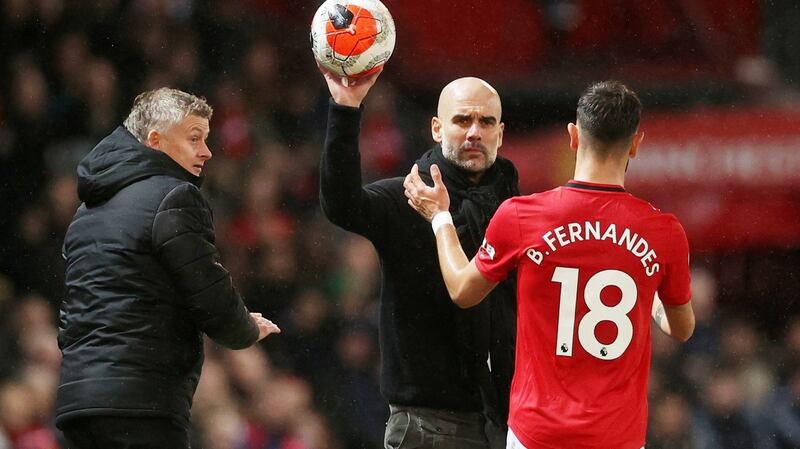 Manchester City manager Pep Guardiola hands the ball to Manchester United’s Bruno Fernandes as Manchester United manager Ole Gunnar Solskjaer looks on. Photograph: Carl Recine/Reuters