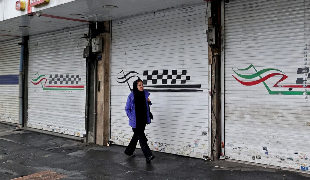 A woman walks past a closed shop along Satarkhan street in Iran's capital Tehran. Photograph: Atta Kenare/AFP via Getty Images