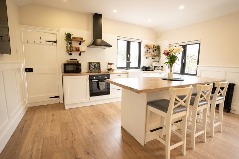 The kitchen units are white with wood-effect countertops, and there is a central island/breakfast bar in the same style.