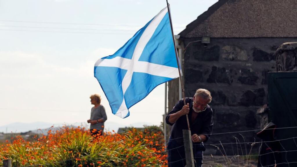 Fear ag cur bhratach na hAlban in airde tigh s’aige féin ar Leòdhas. grianghraf: reuters/cathal mcnaughton.