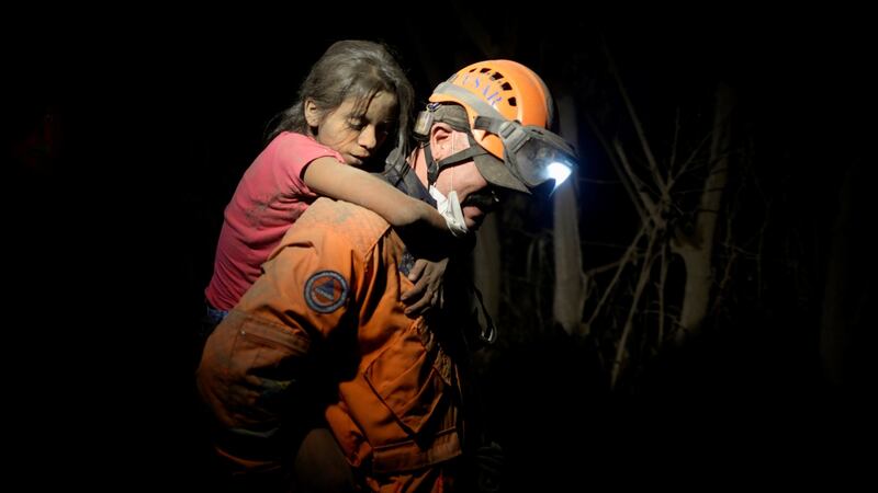 A rescue worker carries a child covered with ash. Photograph: Reuters