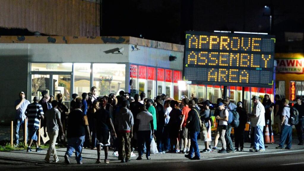 Demonstrators take a break from walking at the approved assembly area set up for them while they protest the shooting death of Michael Brown in Ferguson, Missouri, USA, last night. Photograph: Larry W Smith/EPA.