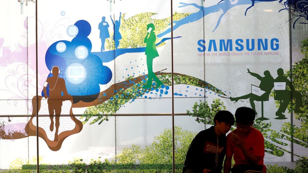Children look at a mobile phone in front of an advertisement of Samsung Electronic at its store in Seoul, South Korea.