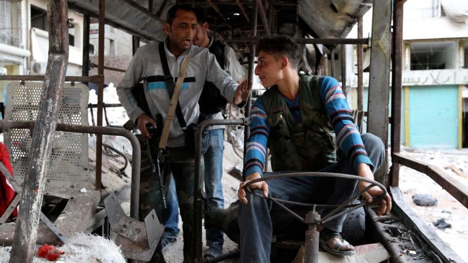 Free Syrian Army fighters play around inside a damaged bus in Ashrafieh, Aleppo. Photograph: Muzaffar Salman/Reuters