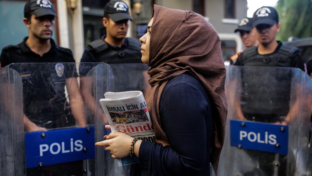 A woman holding the Ozgur Gundem newspaper, one of the outlets ordered to close by a Turkish court. Photograph: Yasin Akgul/AFP/Getty Images