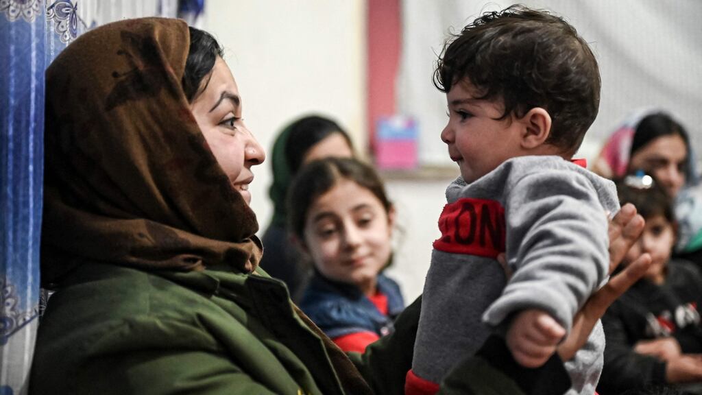Sohail Ahmadi (R), who was separated from his parents at the airport in the chaos of the US evacuation of Afghanistan in August 2021, is held by the wife of Hamid Safi, a taxi driver who found Sohail on the ground at Kabul airport and tracked down the family, at Sohail’s grandfather’s house in Kabul on January 9, 2022. Photograph: Mohd Rasfan / AFP via Getty Images