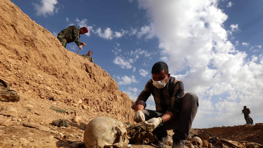 A man inspects the remains of members of the Yazidi minority killed by Islamic State after Kurdish forces discovered a mass grave near the village of Sinuni, in the northwestern Sinjar area of Iraq, in February 2015. Photograph: Safin Hamed/AFP/Getty Images