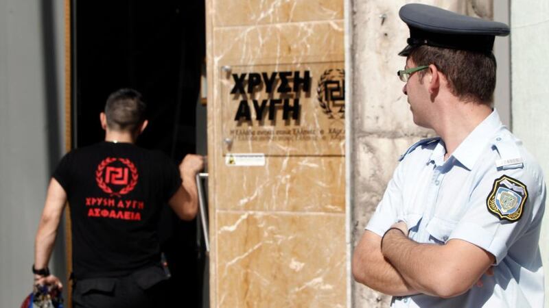 A Greek police officer watches as a member of the Golden Dawn far-right party enters the party’s headquarters in Athens. Photogrpah: John Kolesidis/Reuters