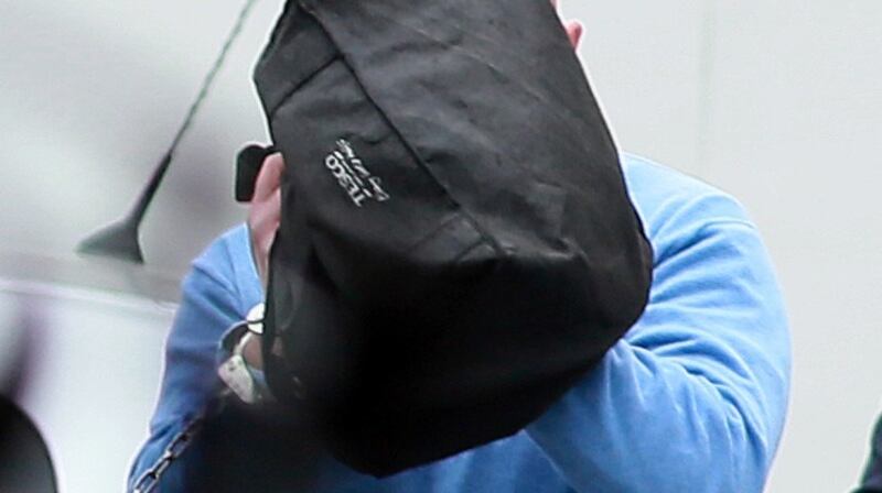 Michael Murray hides his face as he is led away following a previous court appearance. File photograph: Courts Collins