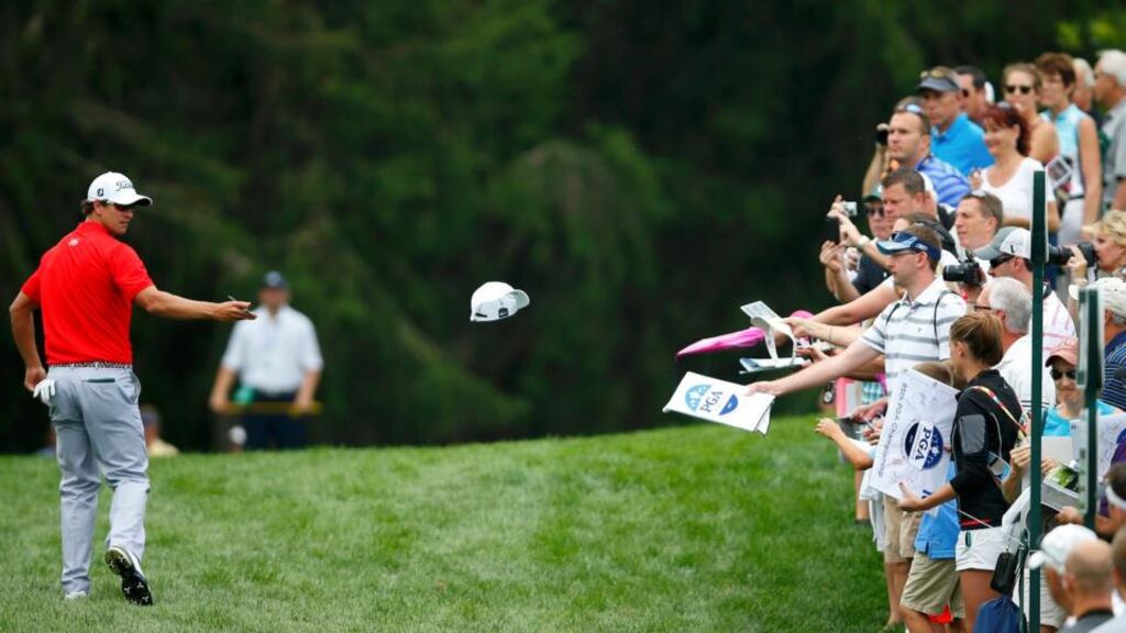 Australia’s Adam Scott tosses an autographed hat to the gallery during a practice round for the 2013 PGA Championship golf tournament at Oak Hill Country Club in Rochester, New York. Photo: Jeff Haynes/Reuters
