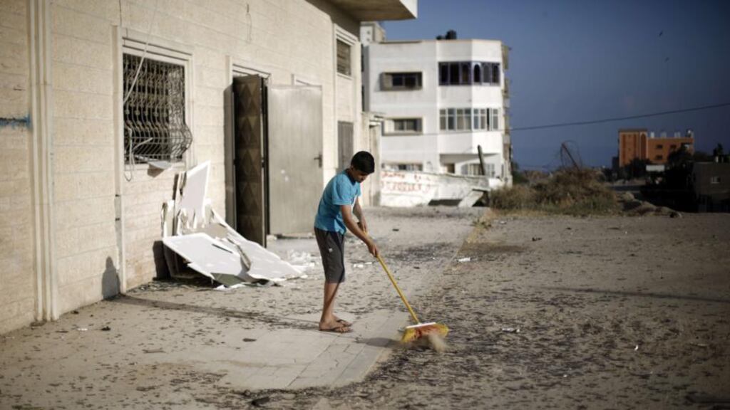 A Palestinian boy cleans debris near a training base of the Ezzedine al-Qassam brigades, the military wing of Hamas, in Gaza City, after Israeli warplanes struck multiple militant targets in the Palestinian coastal strip. Photograph: Mohammed Abed/AFP/Getty Images