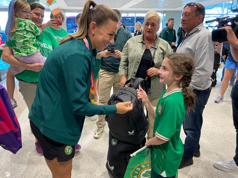 Katie McCabe signing a jersey at the airport