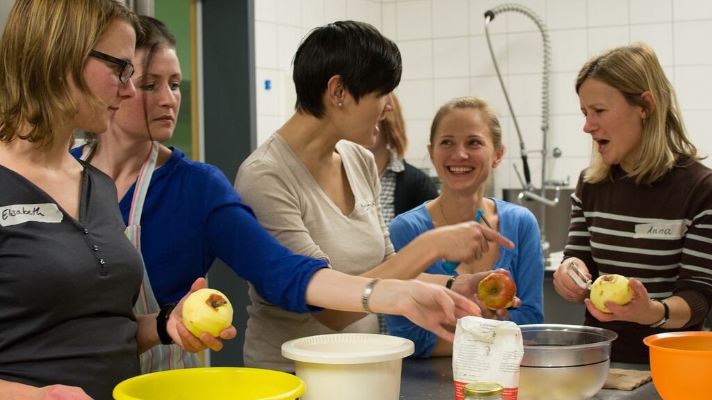 Fionnuala Zinnecker (second from left) helps participants to peel apples for a tart.