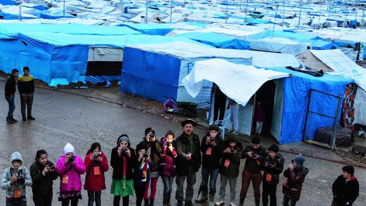 Reza at Kawergosk Refugee Camp, in Iraqi Kurdistan, teaching young refugee children the art of photography. Credit: Reza Visual Academy