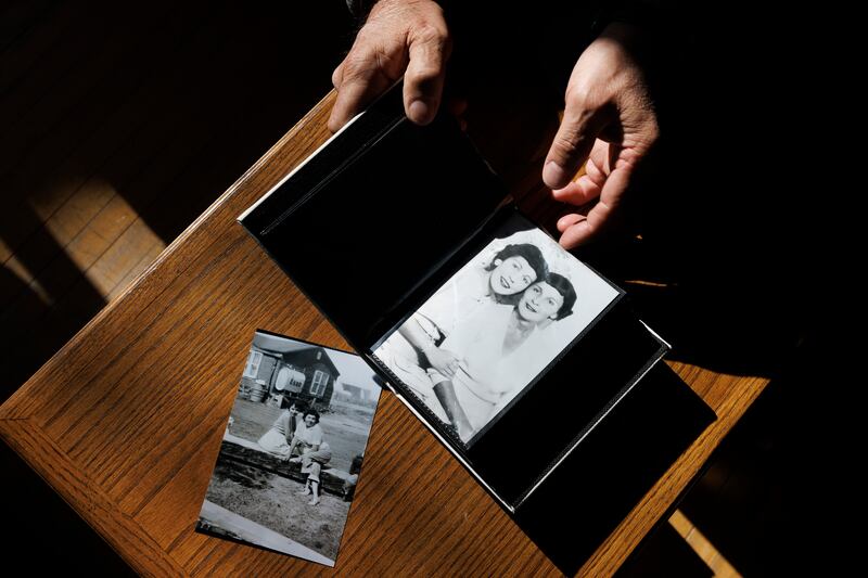Eddy Ambrose leafing through a photo album featuring pictures of his biological mother and aunt, neither of whom he knew, at home in Winnipeg. Photograph: Nasuna Stuart-Ulin/The New York Times