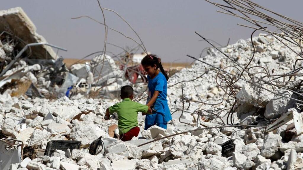 A girl helps her brother make his way through the rubble of a damaged house in the eastern Hama countryside. Photograph: Reuters