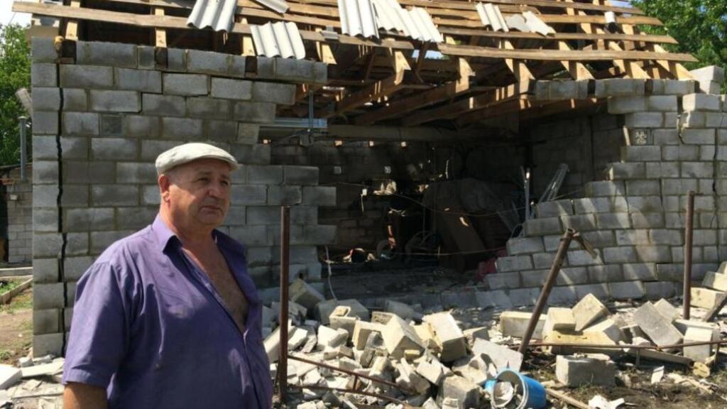 Nikolai Fyodorich examines a neighbour’s house in a Donetsk suburb, which was hit by deadly shellfire at the weekend. Photograph: Daniel McLaughlin