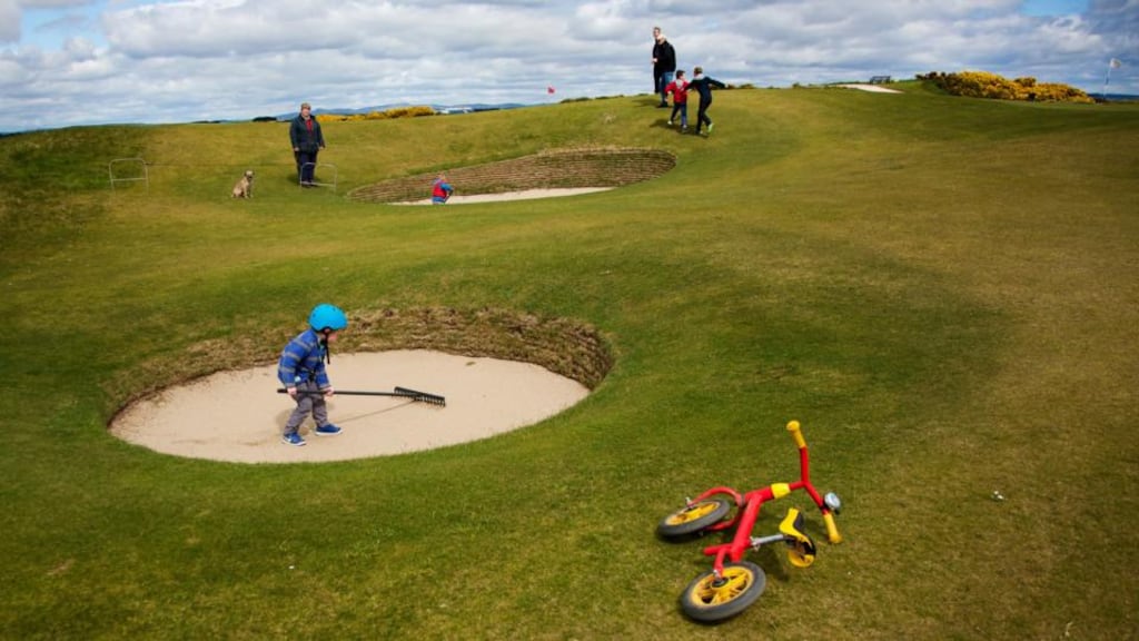 Locals and tourists wander the grounds of the Old Course, the birthplace of golf, in St Andrews. All are welcome om Sunday bar golfers. Photograph: Kieran Dodds/The New York Times