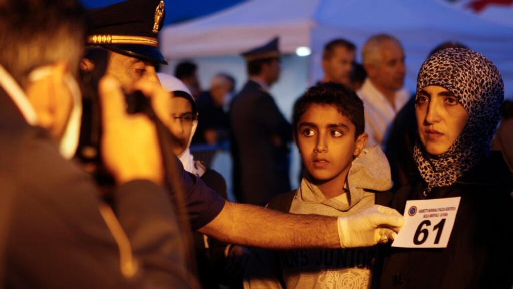 Italian police take pictures of migrants as they arrive with a group that includes Syrian and Palestinian refugees at Catania harbour in the island of Sicily yesterday. REUTERS/Antonio Parrinello