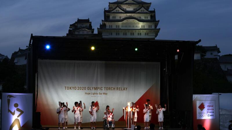 Tokyo 2020 Olympics torch bearers wave as they pose for a group photograph, with the World Heritage Himeji Castle in the background on Sunday. Photograph: Buddhika Weerasinghe/Getty Images
