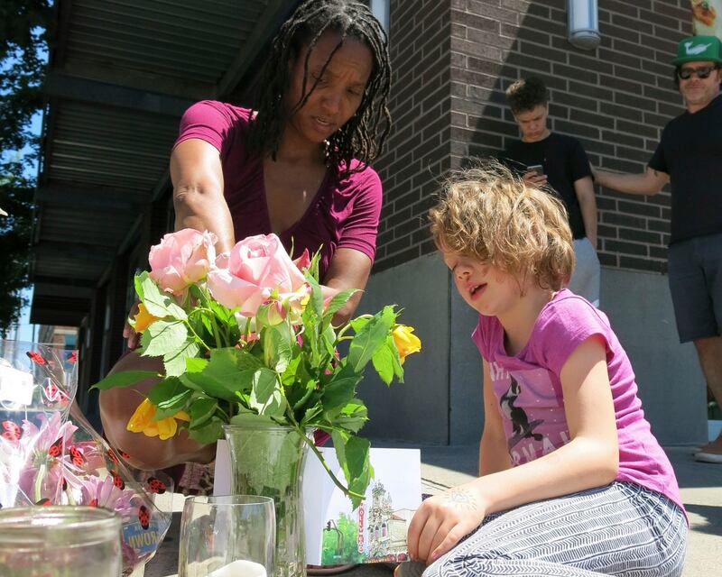 Angel Sauls, left, helps her stepdaughter, Coco Douglas arrange a sign and some painted rocks she made for a memorial in Portland, Oregon for two bystanders who were stabbed to death while trying to stop a man who was yelling anti-Muslim slurs and acting aggressively toward two young women. Photgraph: AP/Gillian Flaccus