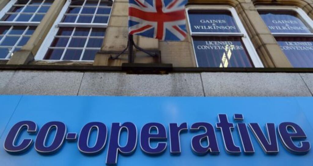 A logo sits on a sign outside a Co-Operative Bank Plc bank branch as a British union flag flies above in Keighley, UK. Photograph: Nigel Roddis/Bloomberg