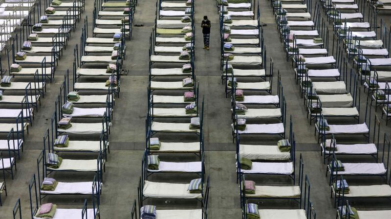 A worker walks among beds in a convention centre converted into a temporary hospital in Wuhan. Photograph: Chinatopix via AP