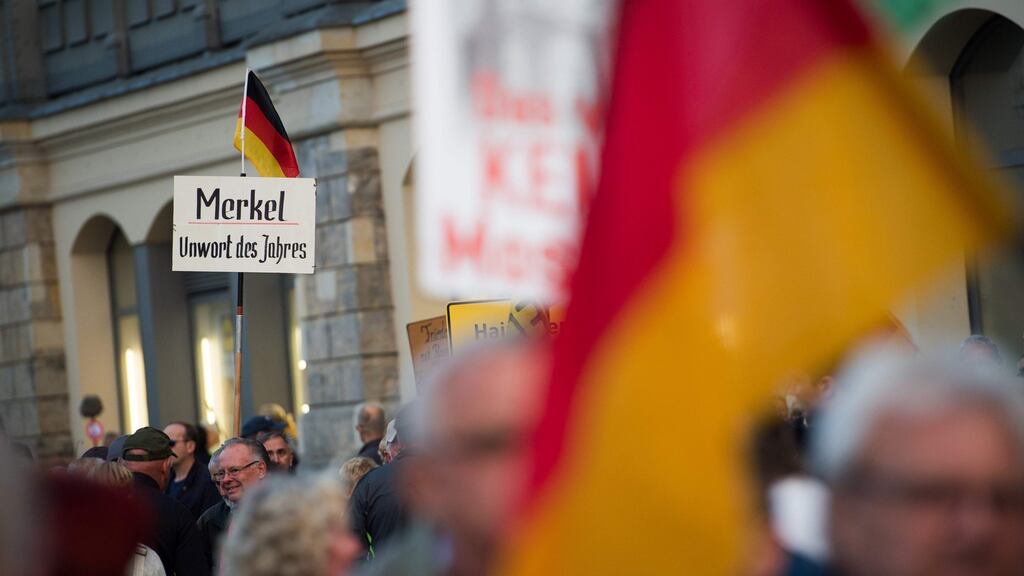 Supporters of the anti-immigrant Pegida movement hold up a banner reading “Merkel – Non-Word of the Year” during a rally in Dresden. Photograph: Arno Burgi/AFP/Getty Images