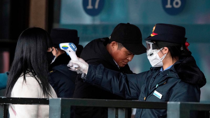Security personnel checking the temperature of a passenger wearing a face mask at Beijing Railway Station in Beijing. Photograph: Noel Celis/AFP/Getty Images
