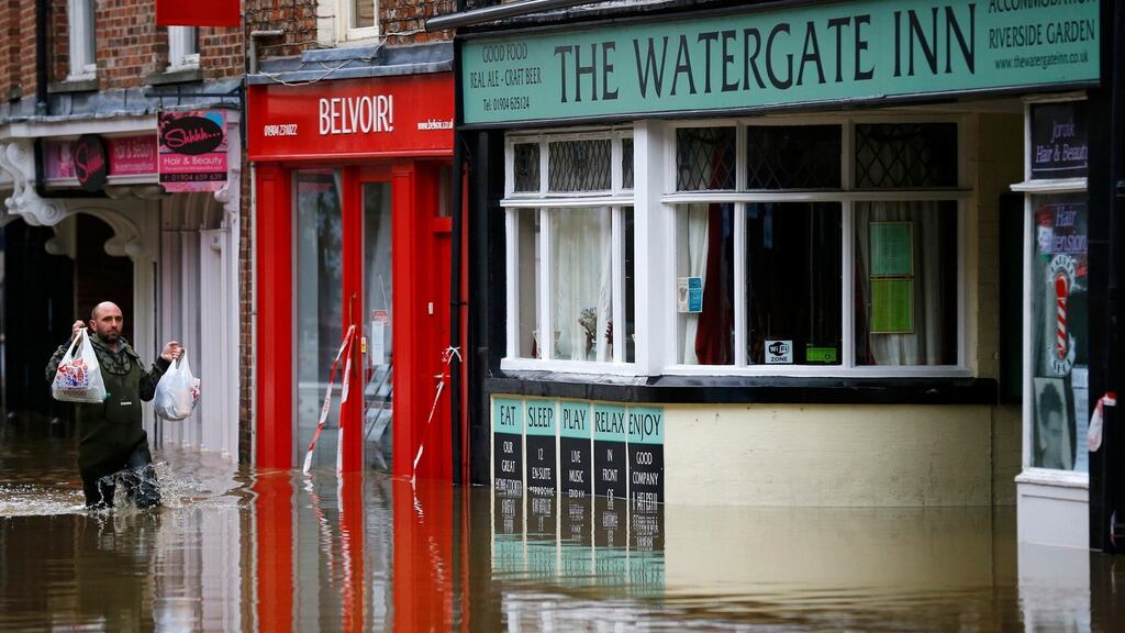 A man carries groceries into a flooded pub in York city centre: 500 properties have been flooded in the city. Photograph: Darren Staples/Reuters