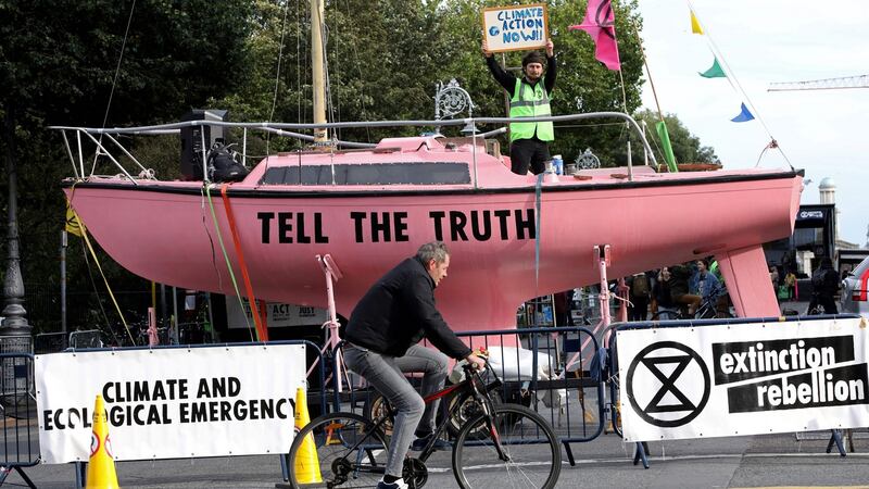 An activist stands aboard a pink boat blockading a road near Government Buildings during Extinction Rebellion protests in Dublin. There is now unprecedented public engagement and willingness to take action on carbon emissions. Photograph: Paul Faith/AFP via Getty