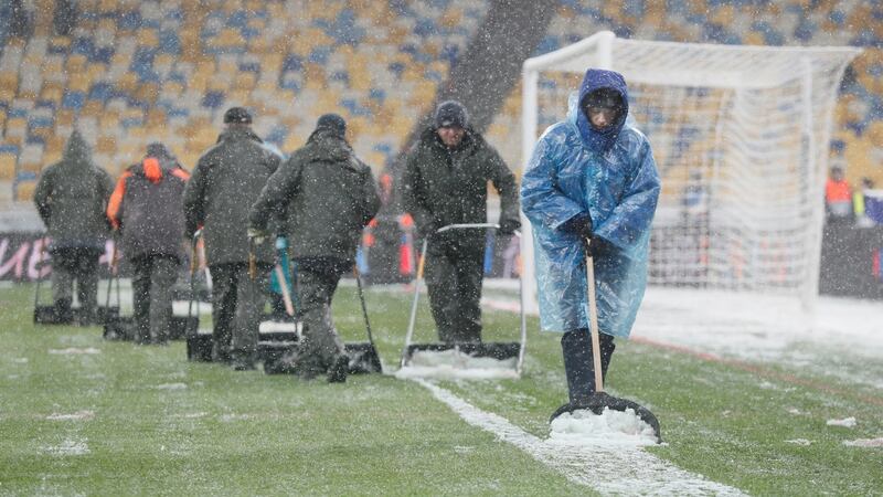 Workers clear snow from the pitch in Kyiv before the match. Photo: Sergey Dolzhenko/Getty Images