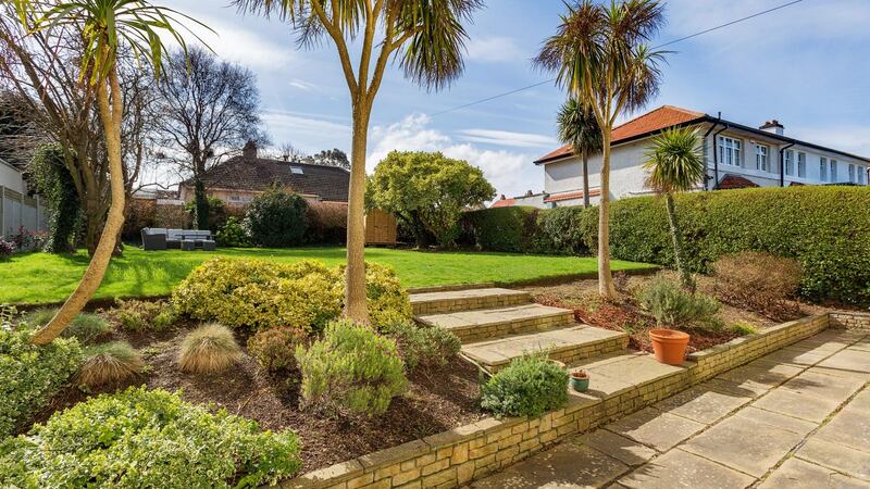 Steps lead up from a patio at the back of the house past raised flowerbeds to a wide 100ft-long rear lawn