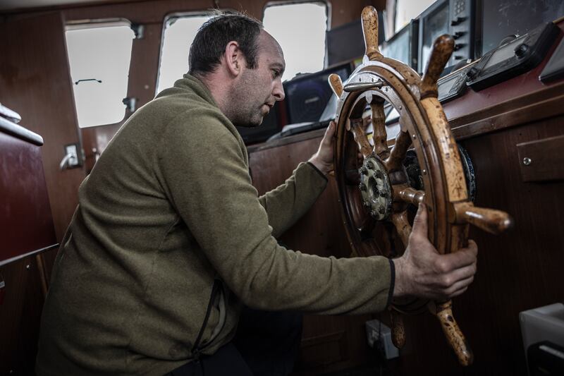 David O’Neill, the skipper of the Aquila, removes the boat’s steering wheel after the ship’s final voyage. Photograph: Finbarr O'Reilly/New York Times