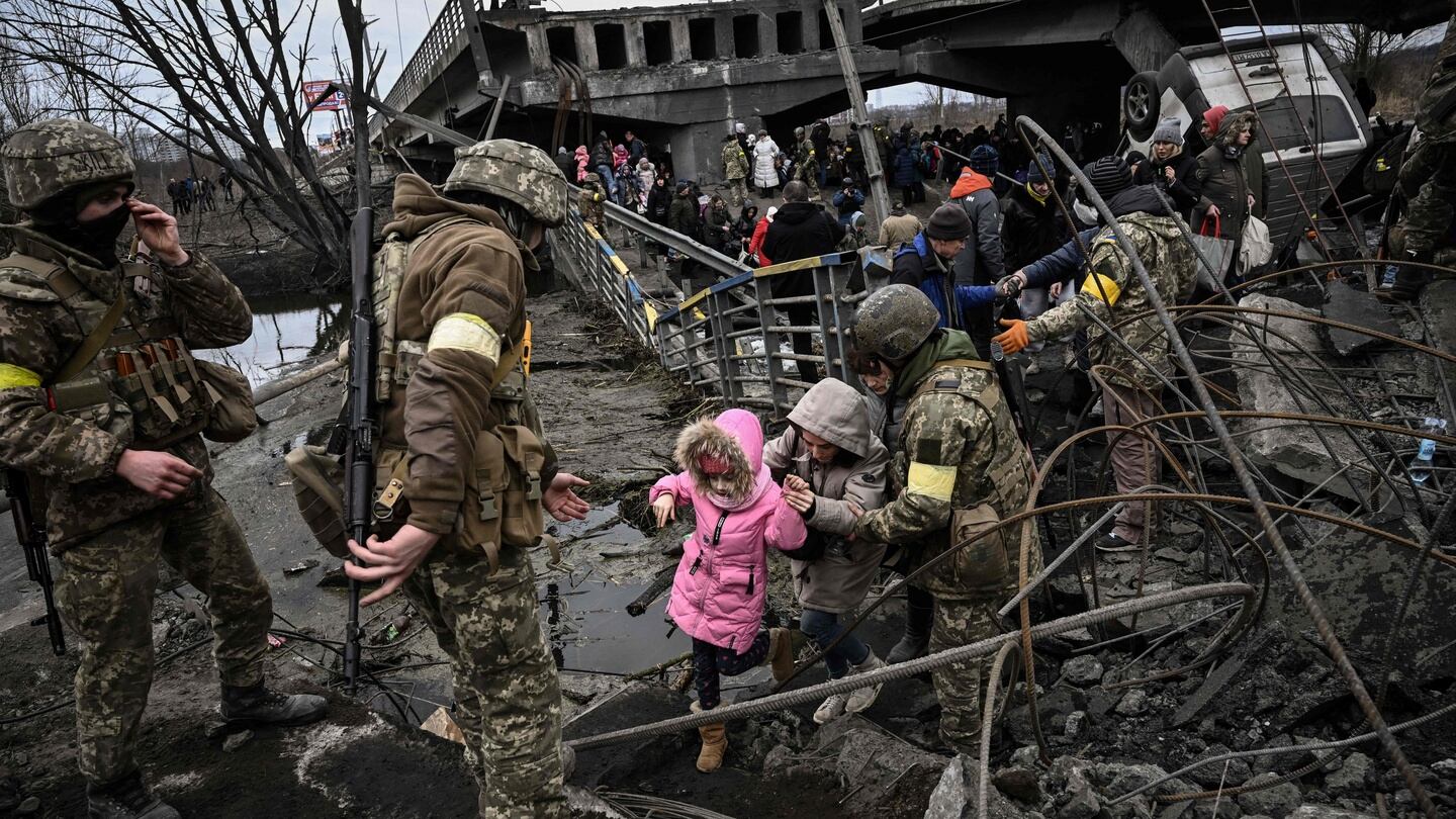 A girl is helped make her way through rubble as Ukrainians seek to get past a destroyed bridge as they evacuate the city of Irpin, northwest of Kyiv, during heavy shelling and bombing on Saturday. Photograph: Aris Messinis/AFP/Getty