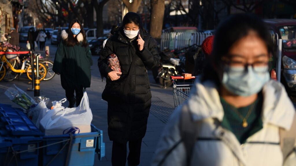 People wear protective face masks as they walk on a street in Beijing on Monday. Photograph: Greg Baker/AFP via Getty Images